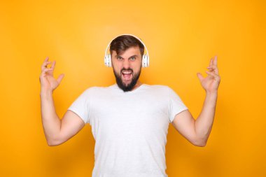 Adam dişlerini gösteriyor, ellerini kaldırıyor ve müzik dinliyor.