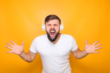 Beyaz kulaklıklı bir adam müzik dinler ve yüksek sesle şarkı söyler, ellerini kaldırır..