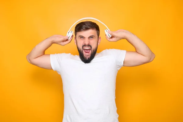 Ein Mann Hält Kopfhörer Vor Sich Steht Auf Gelbem Hintergrund — Stockfoto
