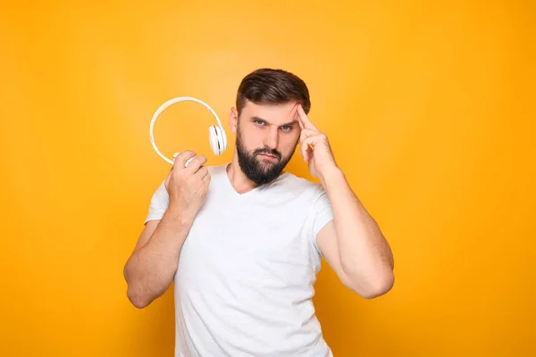 bearded man, music lover holds white headphones in front of him.