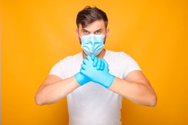 Tıbbi maskeli ve steril tek kullanımlık eldivenli bir adam çeşitli el hareketleri sergiliyor..