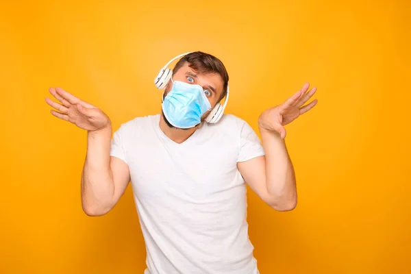 Seorang Pria Mengenakan Masker Medis Wajahnya Dan Headphone Musik Menunjukkan — Stok Foto