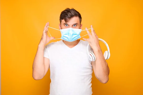 Adam Elinde Beyaz Bir Müzik Kulaklığı Tutarken Yüzüne Tıbbi Maske — Stok fotoğraf