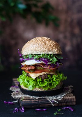 hamburger on a small cast-iron frying pan on a rustic-style tray