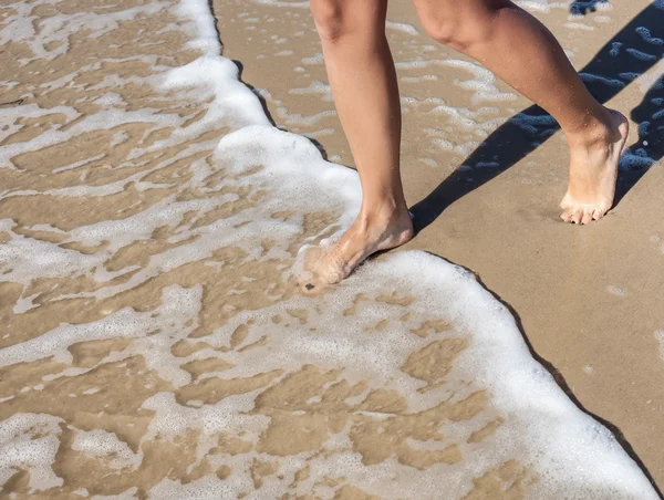 Женские ноги, шагающие в море Лицензионные Стоковые Изображения