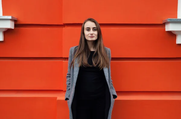 Junge Frau an der orangefarbenen Wand — Stockfoto