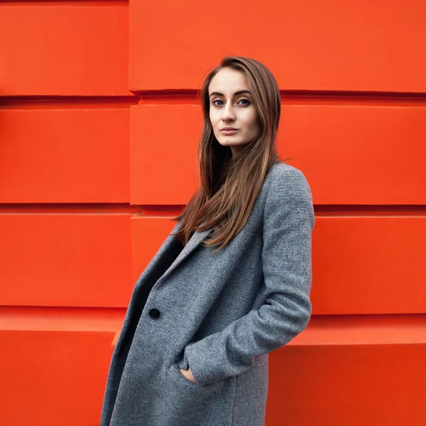 Junge Frau an der orangefarbenen Wand — Stockfoto