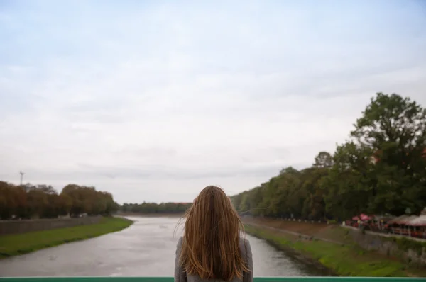 Frau blickt auf die verschwommene Flusslandschaft Stockbild