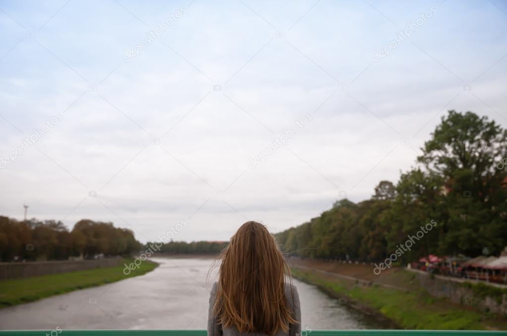 woman looks out over the blurred river landscape