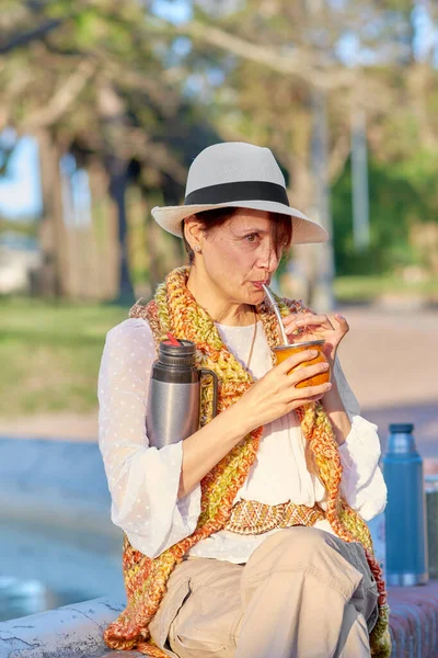 Kadınlar, bohem zanaatkarlar gibi giyinmiş, açık hava parkında geleneksel bir yerba eşinin tadına bakar..