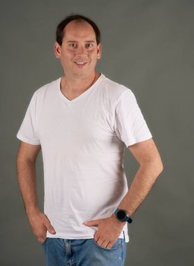 Gri arka planda elleri cebinde kel bir adamın portresi. Beyaz tişörtlü sıradan ve profesyonel tarzda. Temiz ve çok yönlü resim.