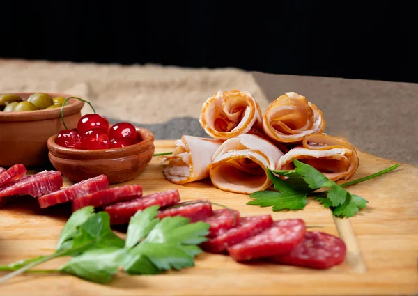 Söğüş et, kiraz ve zeytinli ahşap tahta zarif bir şekilde dizilmiş. Yayın tasarımı, sosyal medya veya profesyonel gıda içeriği için ideal.