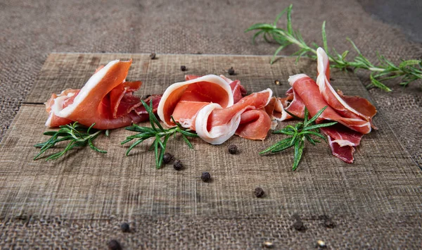 Kavrulmuş jambon dilimleri, biberiye ve sade ahşap üzerine karabiber. Sıcak ve zarif bir kompozisyon, mutfak fotoğrafçılığı ve yemek yayıncılığı için ideal..