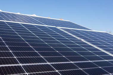 Güneş panelleri açık mavi bir gökyüzünün altında fayanslı bir çatıya monte edilir. Kurulumda konut kullanımı için çevre dostu enerji üretimi sergileniyor.