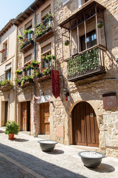 Parlak güneş ışığı, çiçek dolu canlı balkonların yer aldığı taş binalarla dolu kaldırım taşlı caddeleri aydınlatıyor. Sakin bir atmosfer, tarihi bir yerin güzelliğini yansıtır..