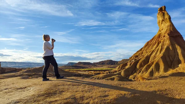 Engebeli arazide duran bir fotoğrafçı, sıcak güneş ışığıyla yıkanmış kaya oluşumlarına odaklanır. Titrek gökyüzü, altın saat boyunca dingin atmosfere katılır..