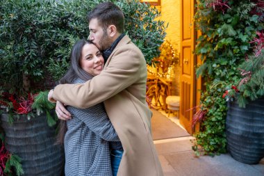 Samimi bir ortamda, iki insan şefkatli bir kucaklaşmayı paylaşır. Kapıdaki sıcak parıltı onların neşeli ifadelerini vurguluyor..