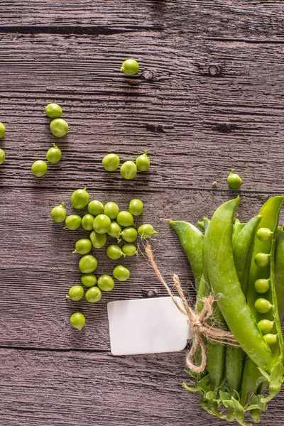 Ervilhas em uma mesa de madeira com etiqueta — Fotografia de Stock