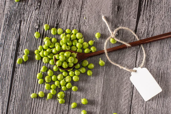 Guisantes en una mesa de madera con cuchara y etiqueta —  Fotos de Stock