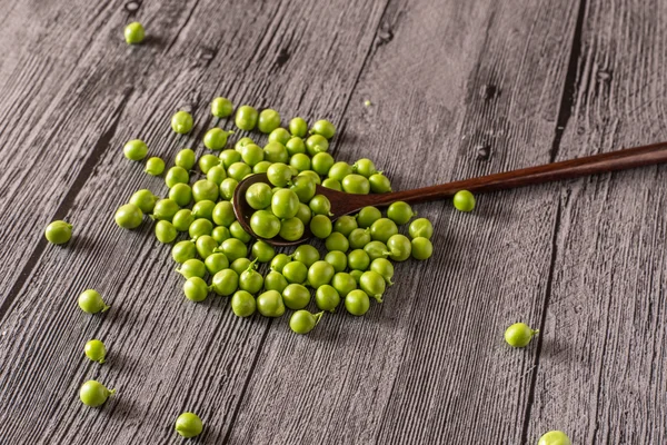 Guisantes en una mesa de madera con cuchara —  Fotos de Stock