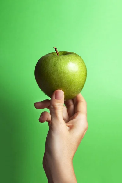 緑の背景とコピースペースのある緑のリンゴを持っている女性の手 — ストック写真