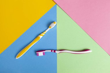 İki renk diş fırçası, sarı ve pembe. Çok renkli bir arka plan. Boşluğu kopyala.
