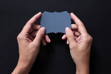 Kopya alanı olan bir kartı tutan eller. Tam renk siyah.