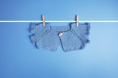 Mavi arka planda asılı mavi bebek kıyafetleri