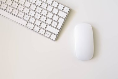 Beyaz arkaplanı olan beyaz klavye ve farenin minimalist üst görünümü