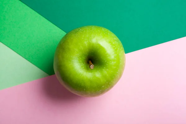 緑とピンクの幾何学的背景に隔離された全体の緑のおばあちゃんのスミスアップルを表示 — ストック写真