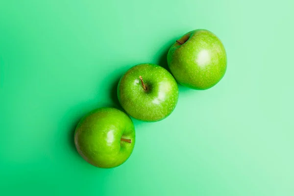 緑の背景に3つの緑のリンゴのトップビュー — ストック写真