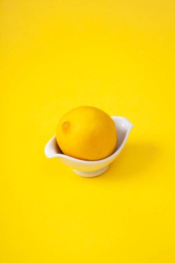Limon beyaz kase ve sarı arka plan. Uzayı kopyala asgari kavram