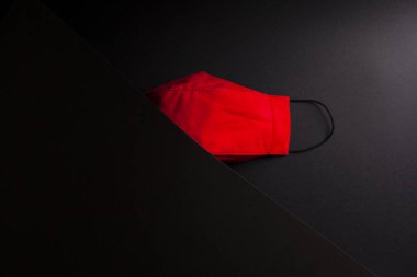 COVID maskesi siyah arkaplanda ikiye bölünmüş ve reklam için yer açılmış.