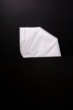 COVID maskesi siyah arkaplanda ikiye bölünmüş ve reklam için yer açılmış.