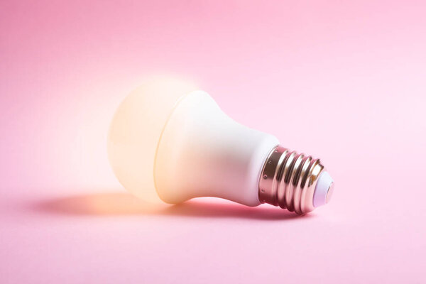 lit light bulb isolated on a pink background. Idea concept.