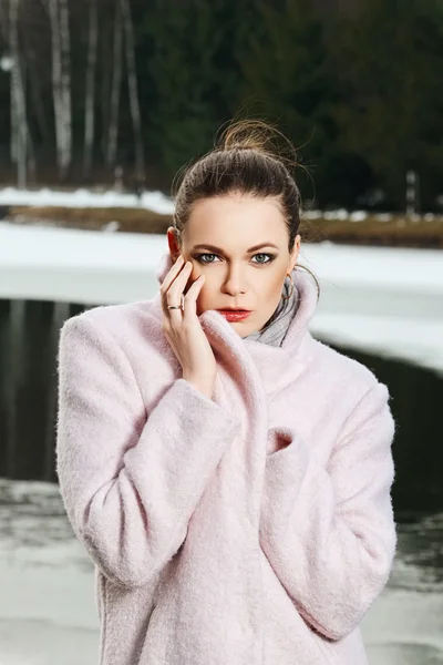 Pretty girl in pink coat near lake in winter forest — Stock Photo, Image
