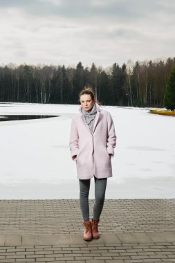 Güzel kız kış ormandaki göl yakınındaki pembe ceket