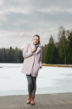 Güzel kız kış ormandaki göl yakınındaki pembe ceket