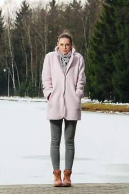 Güzel kız kış ormandaki göl yakınındaki pembe ceket