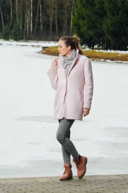 Güzel kız kış ormandaki göl yakınındaki pembe ceket