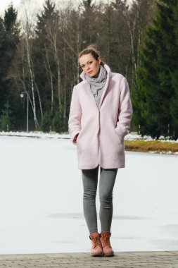 Güzel kız kış ormandaki göl yakınındaki pembe ceket