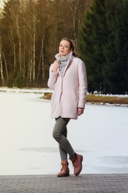 Güzel kız kış ormandaki göl yakınındaki pembe ceket