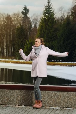 Güzel kız kış ormandaki göl yakınındaki pembe ceket