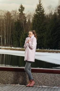 Dondurucu kız kış ormandaki göl yakınındaki pembe ceket