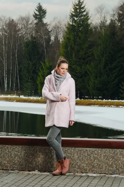 Menina bonita em casaco rosa perto do lago na floresta de inverno — Fotografia de Stock