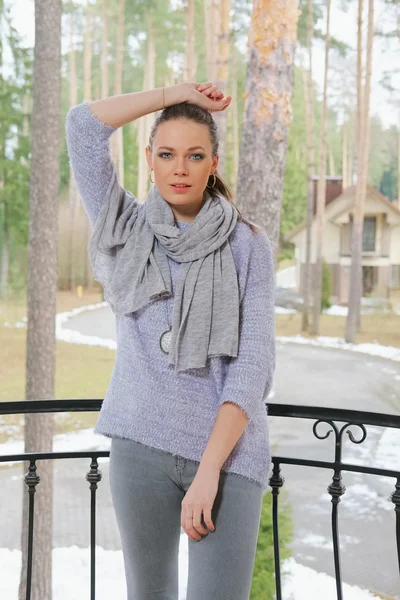 Привлекательная леди в свитере и шарфе, стоящая на балконе — стоковое фото