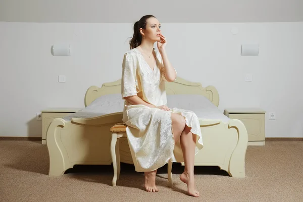 Bela jovem senhora no quarto em seda peignoir perto da cama — Fotografia de Stock