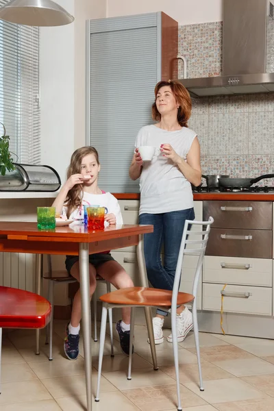 Mãe e filha na cozinha beber chá e comer doce — Fotografia de Stock