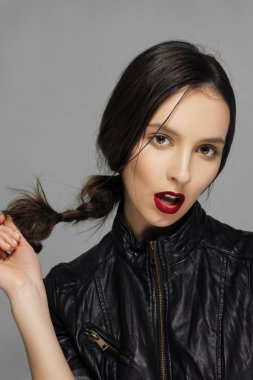 Çekici kız saçları ile oynarken deri ceketli. Kırmızı mat li