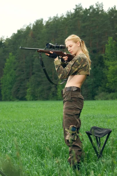 Menina caçador bonita apontando com rifle de caça na madeira exterior . — Fotografia de Stock